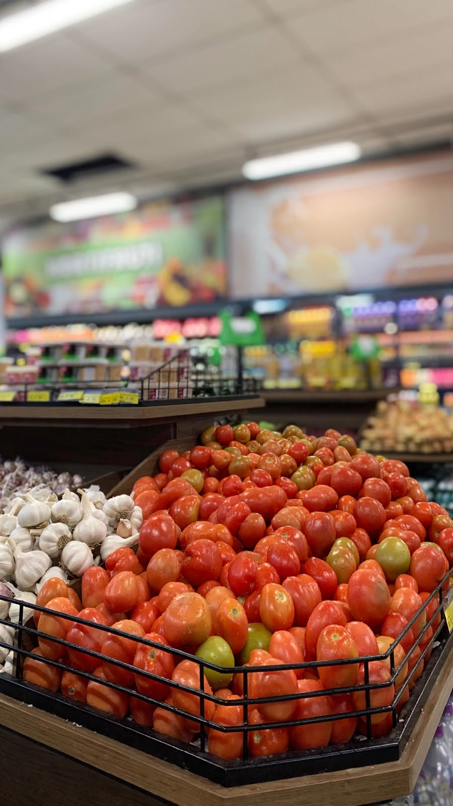 Tomates e alhos frescos em exposição de madeira no hortifruti